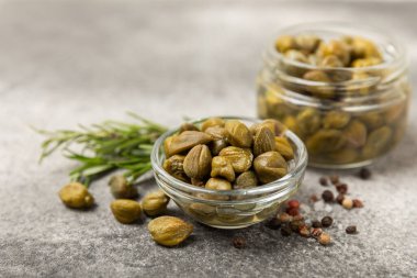 Ahşap mutfak masasında kapari. Deniz tuzu ve biberiyeli kapari. Turşu turşusu. Akdeniz mutfağı malzemesi. Organik baharatlar ve baharatlar. Boşluğu kopyala.