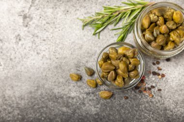 Ahşap mutfak masasında kapari. Deniz tuzu ve biberiyeli kapari. Turşu turşusu. Akdeniz mutfağı malzemesi. Organik baharatlar ve baharatlar. Boşluğu kopyala.