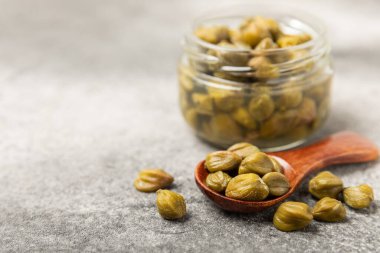 Ahşap mutfak masasında kapari. Deniz tuzu ve biberiyeli kapari. Turşu turşusu. Akdeniz mutfağı malzemesi. Organik baharatlar ve baharatlar. Boşluğu kopyala.