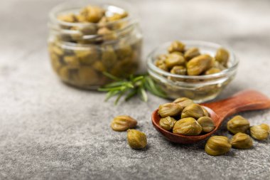 Ahşap mutfak masasında kapari. Deniz tuzu ve biberiyeli kapari. Turşu turşusu. Akdeniz mutfağı malzemesi. Organik baharatlar ve baharatlar. Boşluğu kopyala.