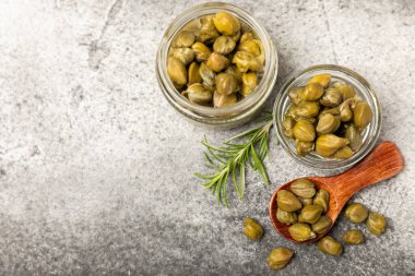 Ahşap mutfak masasında kapari. Deniz tuzu ve biberiyeli kapari. Turşu turşusu. Akdeniz mutfağı malzemesi. Organik baharatlar ve baharatlar. Boşluğu kopyala.