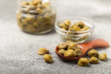 Ahşap mutfak masasında kapari. Deniz tuzu ve biberiyeli kapari. Turşu turşusu. Akdeniz mutfağı malzemesi. Organik baharatlar ve baharatlar. Boşluğu kopyala.