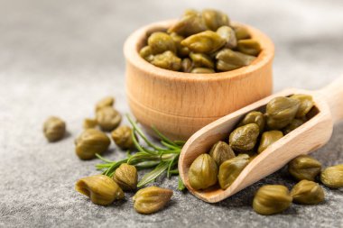 Ahşap mutfak masasında kapari. Deniz tuzu ve biberiyeli kapari. Turşu turşusu. Akdeniz mutfağı malzemesi. Organik baharatlar ve baharatlar. Boşluğu kopyala.