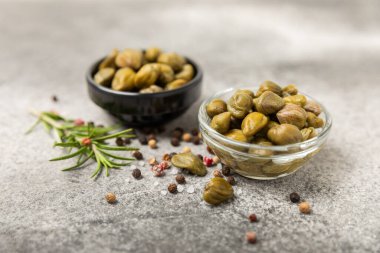 Ahşap mutfak masasında kapari. Deniz tuzu ve biberiyeli kapari. Turşu turşusu. Akdeniz mutfağı malzemesi. Organik baharatlar ve baharatlar. Boşluğu kopyala.