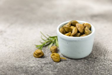 Ahşap mutfak masasında kapari. Deniz tuzu ve biberiyeli kapari. Turşu turşusu. Akdeniz mutfağı malzemesi. Organik baharatlar ve baharatlar. Boşluğu kopyala.