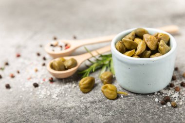 Ahşap mutfak masasında kapari. Deniz tuzu ve biberiyeli kapari. Turşu turşusu. Akdeniz mutfağı malzemesi. Organik baharatlar ve baharatlar. Boşluğu kopyala.