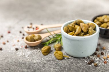 Ahşap mutfak masasında kapari. Deniz tuzu ve biberiyeli kapari. Turşu turşusu. Akdeniz mutfağı malzemesi. Organik baharatlar ve baharatlar. Boşluğu kopyala.