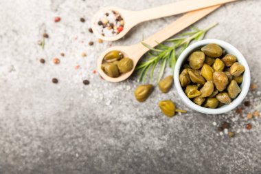 Ahşap mutfak masasında kapari. Deniz tuzu ve biberiyeli kapari. Turşu turşusu. Akdeniz mutfağı malzemesi. Organik baharatlar ve baharatlar. Boşluğu kopyala.