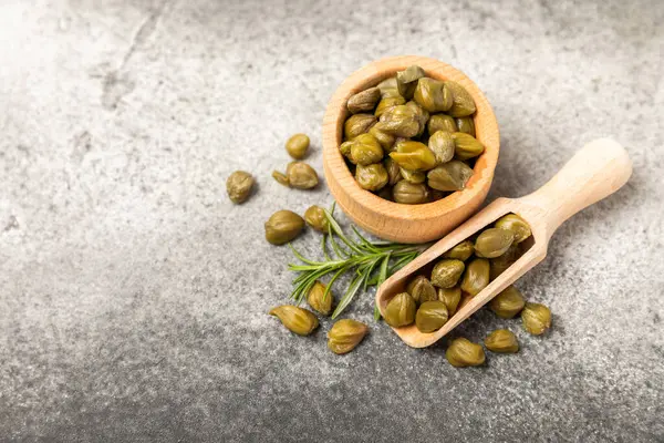 Ahşap mutfak masasında kapari. Deniz tuzu ve biberiyeli kapari. Turşu turşusu. Akdeniz mutfağı malzemesi. Organik baharatlar ve baharatlar. Boşluğu kopyala.