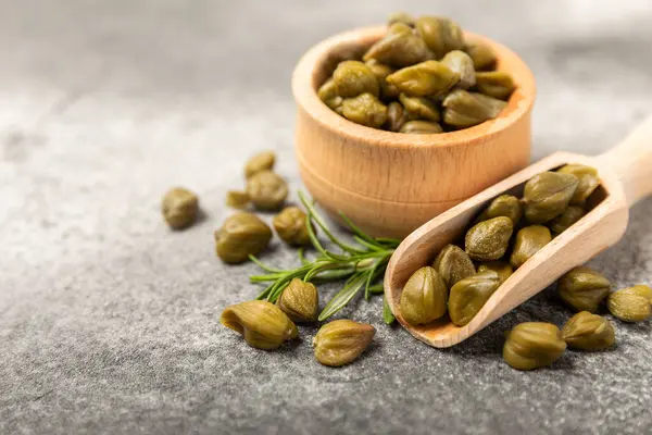 Ahşap mutfak masasında kapari. Deniz tuzu ve biberiyeli kapari. Turşu turşusu. Akdeniz mutfağı malzemesi. Organik baharatlar ve baharatlar. Boşluğu kopyala.