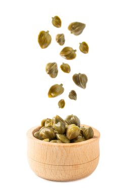 Turşulu kapari kapari yığını üzerine düşüyor. Beyaz bir arka planda izole edilmiş yakın plan..