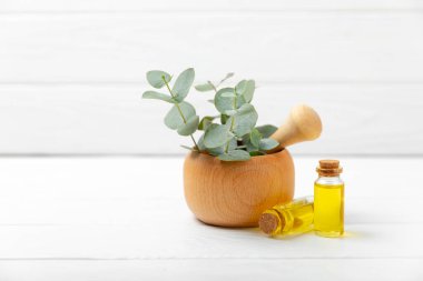 Tahta zeminde okaliptüs yaprakları ve harç. Alternatif tıp ve doğal kozmetik ürünleri için spa konsepti. Bir şişe gerekli yağ ve bir demet okaliptüs. Organik cilt bakımı 