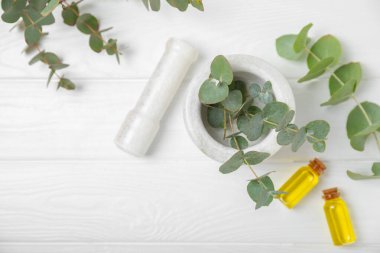 Tahta zeminde okaliptüs yaprakları ve harç. Alternatif tıp ve doğal kozmetik ürünleri için spa konsepti. Bir şişe gerekli yağ ve bir demet okaliptüs. Organik cilt bakımı 