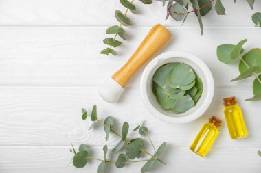 Tahta zeminde okaliptüs yaprakları ve harç. Alternatif tıp ve doğal kozmetik ürünleri için spa konsepti. Bir şişe gerekli yağ ve bir demet okaliptüs. Organik cilt bakımı 
