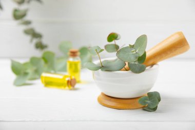 Tahta zeminde okaliptüs yaprakları ve harç. Alternatif tıp ve doğal kozmetik ürünleri için spa konsepti. Bir şişe gerekli yağ ve bir demet okaliptüs. Organik cilt bakımı 