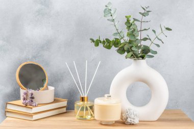 Yeşil okaliptüs, bir vazo tezgahında, çekmecelerden oluşan bir sandıkta duvarın arka planında durur. Aromaterapi. Çok güzel bir okaliptüs buketi. Çiçekler, mumlar ve aroma yayıcı ile minimalist iç mekan..