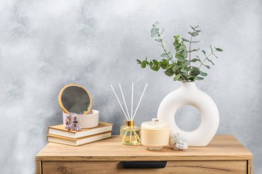 Yeşil okaliptüs, bir vazo tezgahında, çekmecelerden oluşan bir sandıkta duvarın arka planında durur. Aromaterapi. Çok güzel bir okaliptüs buketi. Çiçekler, mumlar ve aroma yayıcı ile minimalist iç mekan..