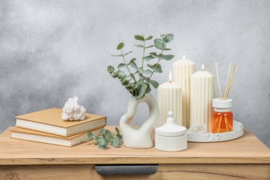 Yeşil okaliptüs, bir vazo tezgahında, çekmecelerden oluşan bir sandıkta duvarın arka planında durur. Aromaterapi. Çok güzel bir okaliptüs buketi. Çiçekler, mumlar ve aroma yayıcı ile minimalist iç mekan..