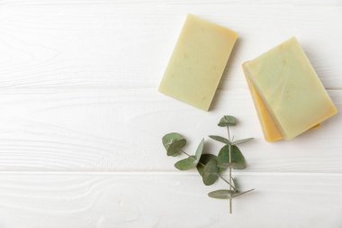 Arkaplanda sabun var. Okaliptüs özlü sabun ve beyaz arka planda doğal otlar. Güzel Doğal sabun kalıpları. El yapımı organik sabun konsepti. Cilt bakımı. Pankart