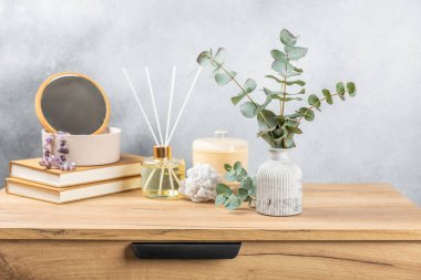 Yeşil okaliptüs, bir vazo tezgahında, çekmecelerden oluşan bir sandıkta duvarın arka planında durur. Aromaterapi. Çok güzel bir okaliptüs buketi. Çiçekler, mumlar ve aroma yayıcı ile minimalist iç mekan..