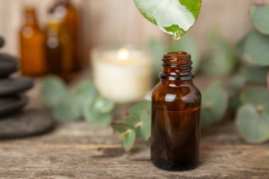 Okaliptüs, ahşap kaplamalı yeşil okaliptüs yapraklı cam bir şişede gerekli yağdır. Aromaterapi konsepti. Spa mı? Kozmetik ve vücut bakımı için doğal organik malzemeler.