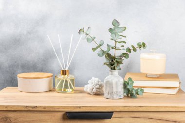 Yeşil okaliptüs, bir vazo tezgahında, çekmecelerden oluşan bir sandıkta duvarın arka planında durur. Aromaterapi. Çok güzel bir okaliptüs buketi. Çiçekler, mumlar ve aroma yayıcı ile minimalist iç mekan..