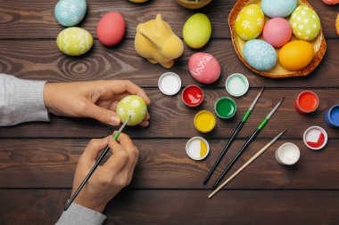 Kadınlar paskalya yumurtalarını mutfak ahşap masasında boyar. Mutlu Paskalya kutlaması kavramları. Farklı şekillerde renkli paskalya yumurtaları..