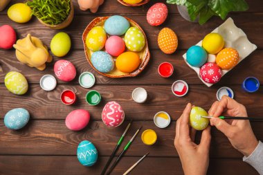 Kadınlar paskalya yumurtalarını mutfak ahşap masasında boyar. Mutlu Paskalya kutlaması kavramları. Farklı şekillerde renkli paskalya yumurtaları..