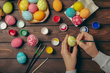 Kadınlar paskalya yumurtalarını mutfak ahşap masasında boyar. Mutlu Paskalya kutlaması kavramları. Farklı şekillerde renkli paskalya yumurtaları..