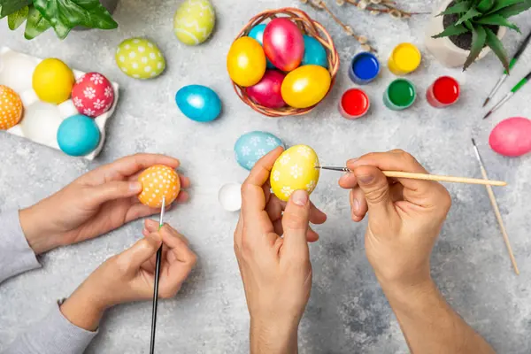 Family painted Easter eggs at the kitchen table.Happy Easter celebration concept.Colorful Easter eggs with different patterns.Paints,decorations for coloring eggs for holiday.Creative background.