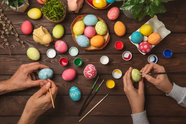 Family painted Easter eggs at the kitchen table.Happy Easter celebration concept.Colorful Easter eggs with different patterns.Paints,decorations for coloring eggs for holiday.Creative background.