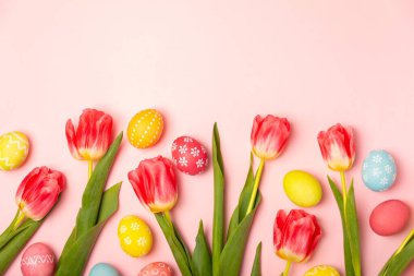 Paskalya yumurtaları ve parlak pembe arka planda bir buket lale. Paskalya kutlaması. El yapımı renkli Paskalya yumurtaları. Mesaj için yer. Boşluğu kopyala.