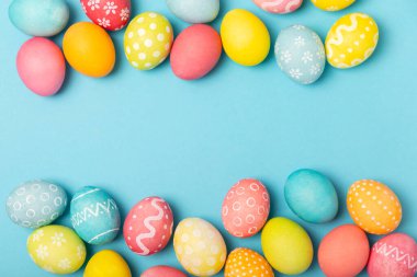 Parlak mavi arka planda Paskalya yumurtaları. Paskalya kutlaması. El yapımı renkli Paskalya yumurtaları. Mesaj için yer. Boşluğu kopyala.