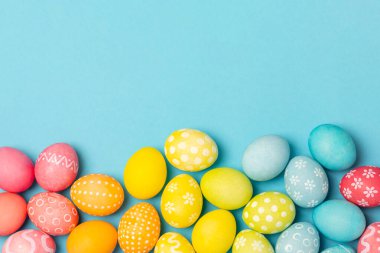 Parlak mavi arka planda Paskalya yumurtaları. Paskalya kutlaması. El yapımı renkli Paskalya yumurtaları. Mesaj için yer. Boşluğu kopyala.