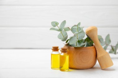 Tahta zeminde okaliptüs yaprakları ve harç. Alternatif tıp ve doğal kozmetik ürünleri için spa konsepti. Bir şişe gerekli yağ ve bir demet okaliptüs. Organik cilt bakımı 