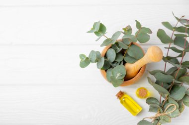 Tahta zeminde okaliptüs yaprakları ve harç. Alternatif tıp ve doğal kozmetik ürünleri için spa konsepti. Bir şişe gerekli yağ ve bir demet okaliptüs. Organik cilt bakımı 