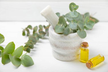 Tahta zeminde okaliptüs yaprakları ve harç. Alternatif tıp ve doğal kozmetik ürünleri için spa konsepti. Bir şişe gerekli yağ ve bir demet okaliptüs. Organik cilt bakımı 