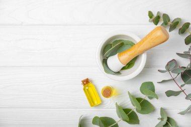 Tahta zeminde okaliptüs yaprakları ve harç. Alternatif tıp ve doğal kozmetik ürünleri için spa konsepti. Bir şişe gerekli yağ ve bir demet okaliptüs. Organik cilt bakımı 