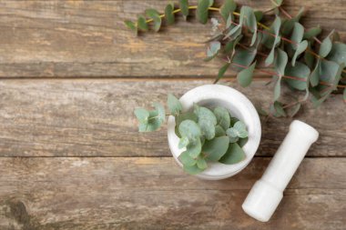 Tahta zeminde okaliptüs yaprakları ve harç. Alternatif tıp ve doğal kozmetik ürünleri için spa konsepti. Bir şişe gerekli yağ ve bir demet okaliptüs. Organik cilt bakımı 