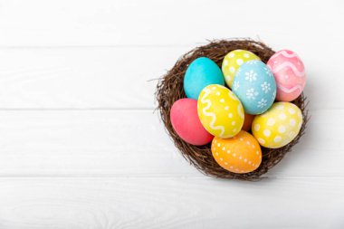 Yuvada renkli Paskalya yumurtaları ve ahşap bir masanın üzerinde bir buket lale. Paskalya kutlaması. El yapımı renkli Paskalya yumurtaları. Mesaj için yer. Boşluğu kopyala