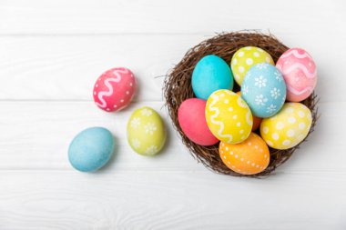 Yuvada renkli Paskalya yumurtaları ve ahşap bir masanın üzerinde bir buket lale. Paskalya kutlaması. El yapımı renkli Paskalya yumurtaları. Mesaj için yer. Boşluğu kopyala