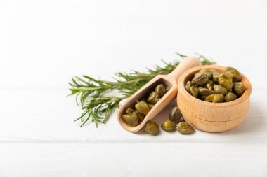 Ahşap mutfak masasında kapari. Deniz tuzu ve biberiyeli kapari. Turşu turşusu. Akdeniz mutfağı malzemesi. Organik baharatlar ve baharatlar. Boşluğu kopyala.