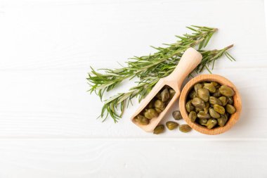 Ahşap mutfak masasında kapari. Deniz tuzu ve biberiyeli kapari. Turşu turşusu. Akdeniz mutfağı malzemesi. Organik baharatlar ve baharatlar. Boşluğu kopyala.