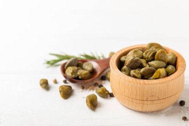 Ahşap mutfak masasında kapari. Deniz tuzu ve biberiyeli kapari. Turşu turşusu. Akdeniz mutfağı malzemesi. Organik baharatlar ve baharatlar. Boşluğu kopyala.