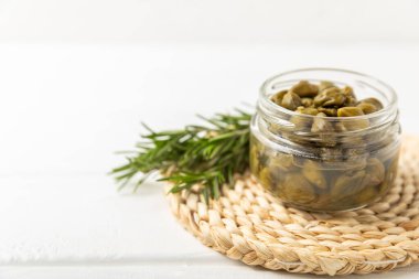 Ahşap mutfak masasında kapari. Deniz tuzu ve biberiyeli kapari. Turşu turşusu. Akdeniz mutfağı malzemesi. Organik baharatlar ve baharatlar. Boşluğu kopyala.