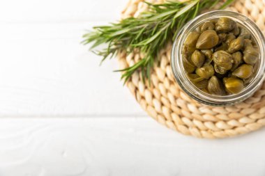 Ahşap mutfak masasında kapari. Deniz tuzu ve biberiyeli kapari. Turşu turşusu. Akdeniz mutfağı malzemesi. Organik baharatlar ve baharatlar. Boşluğu kopyala.