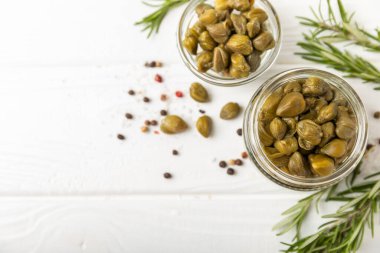 Ahşap mutfak masasında kapari. Deniz tuzu ve biberiyeli kapari. Turşu turşusu. Akdeniz mutfağı malzemesi. Organik baharatlar ve baharatlar. Boşluğu kopyala.