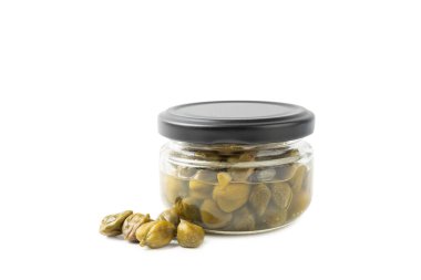 Beyaz arka planda izole edilmiş cam bir kavanozdaki kapari. Terbiye edilmiş kapari tomurcukları, küçük tuzlu kapuçinler, mayalanmış yiyecekler, turşulu kapari grubu. Organik baharatlar ve baharatlar..