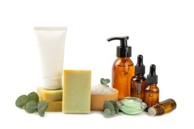 Beyaz zemin üzerinde okaliptüs yaprakları olan güzel bir spa kompozisyonu. Vücut kremi, fırça, maske, temel yağ ve deniz tuzu ile güzellik ve moda spa konsepti. Kozmetik ürün..