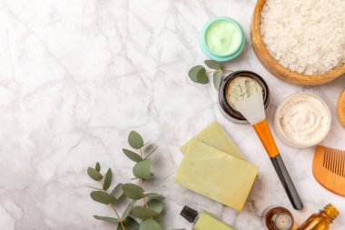 Tahta arka planda okaliptüs yapraklı güzel bir spa kompozisyonu. Vücut kremi, fırça, maske, temel yağ ve deniz tuzu içeren güzellik ve moda spa konsepti. Kozmetik ürün. Boşluğu kopyala.